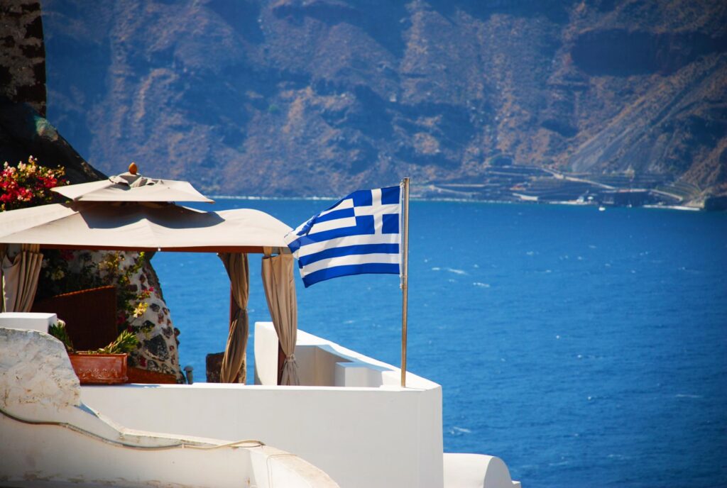 Iconic Santorini building with a Greek flag blowing in the wind