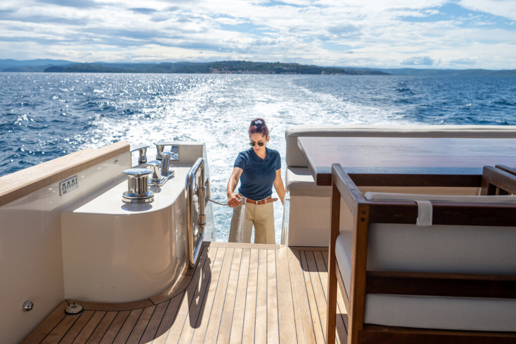 Weibliche Decksklavin reinigt das Deck an Bord einer Yacht.