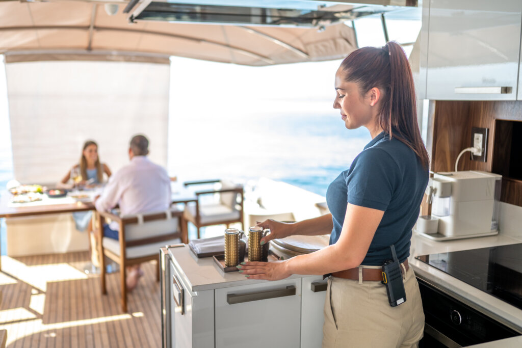 Lächelnde Stewardess arrangiert Salz- und Pfefferstreuer auf einer Luxusyacht.